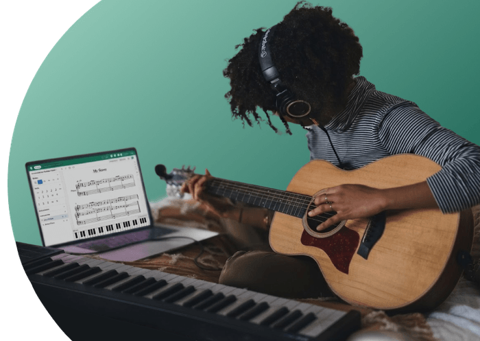 Un élève jouant de la guitare chez lui, à côté d’un ordinateur portable sur lequel est ouvert l’éditeur Flat for Education et d’un clavier MIDI
